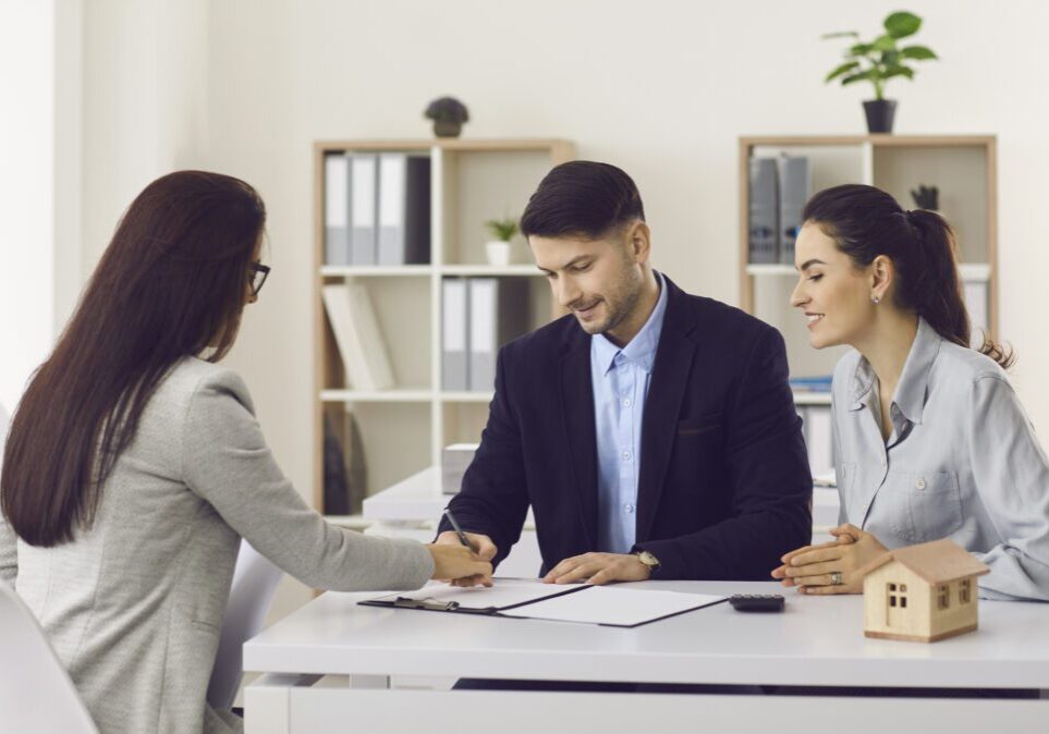 People signing documents at an office table.